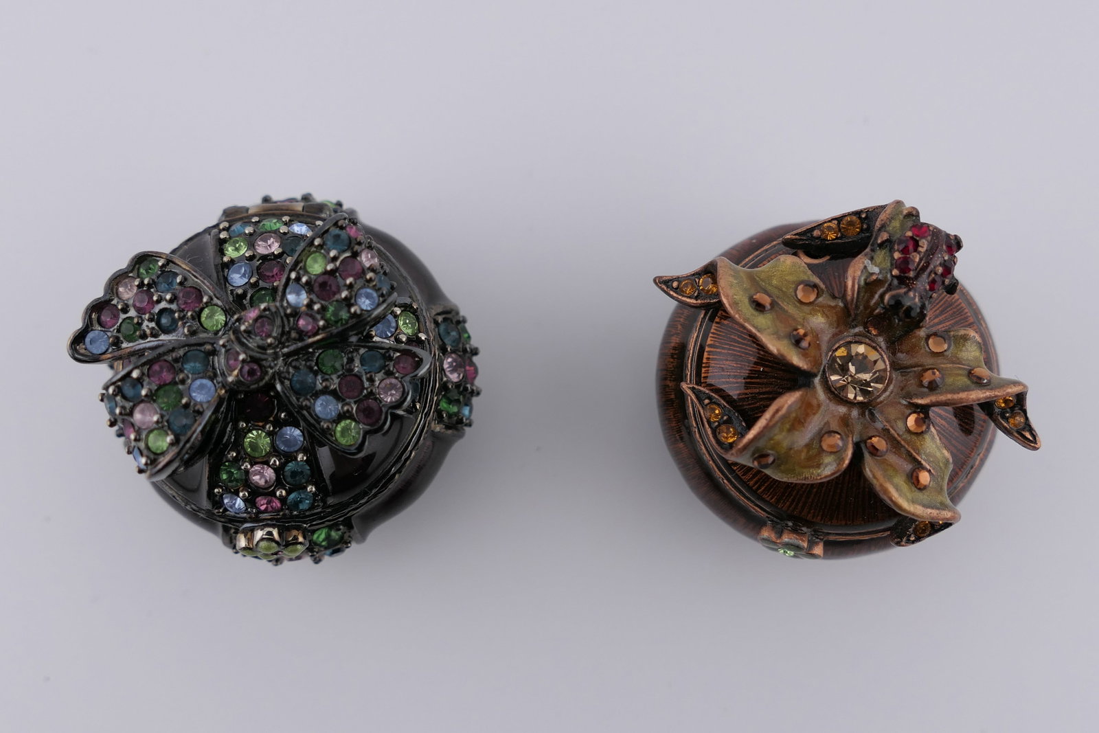 Two Jay Strongwater Floral Trinket Boxes: Two Jay Strongwater enameled trinket boxes featuring molded bow, flower, and ladybug designs, set with colorful Swarovski crystals. Marked on the bottom Jay Strongwater. Excellent condition. Size: 1.2