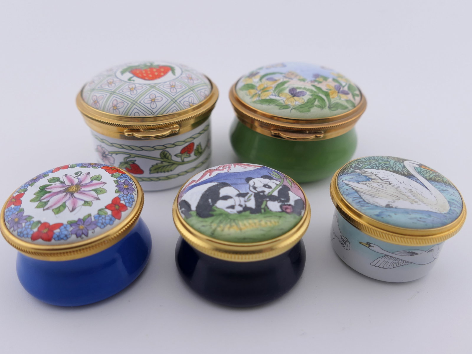 Five Staffordshire trinket Boxes: Five marked Staffordshire trinket boxes with hinge and twist lids, decorated with motifs such as pandas, swans, strawberries, and more. All are marked on the bottom Staffordshire Enamels. Excellent co