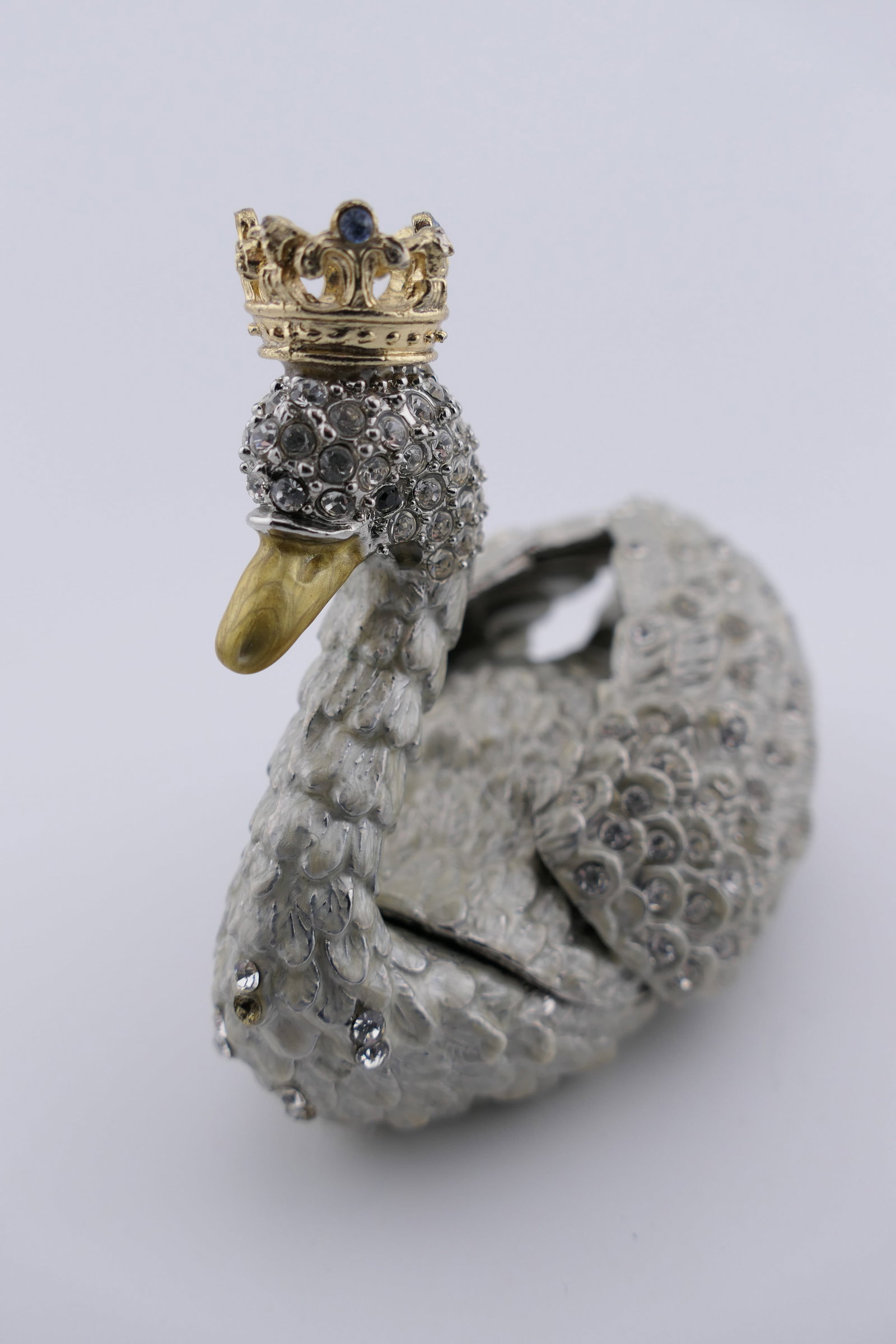 Olivia Riegel Swan Trinket Box: Swan trinket box in metal with an enameled interior, made by Olivia Riegel, encrusted with clear European crystals. The back wings are a lift lid with magnet closures. Good condition, showing some