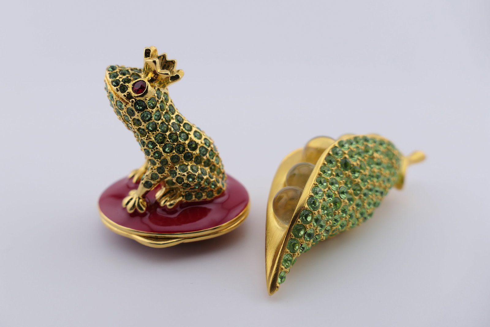 Two Estee Lauder Solid Perfume Compacts: Two Estee Lauder solid perfume compacts in the shape of a frog prince sitting atop a cushion, and peas in a pod. The frog is titled "True Love", is embellished with glass rhinestones, and contains