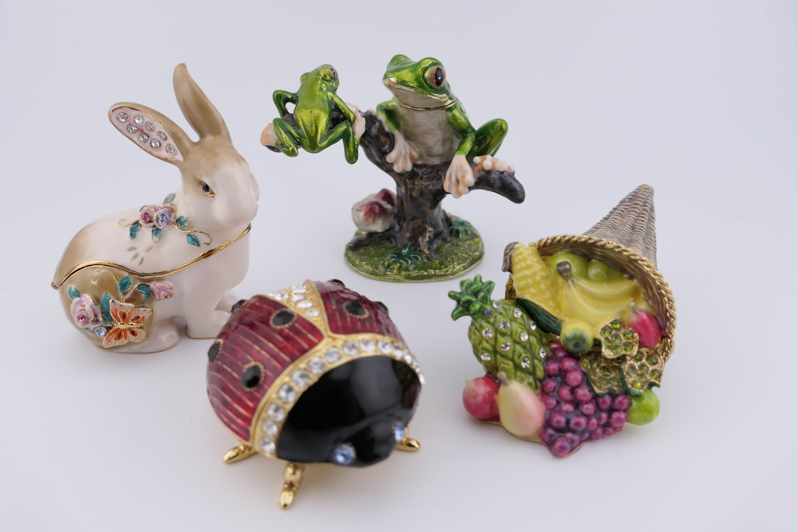 Four Colorful Accent Trinket Boxes: Four colorful accent trinket boxes including ladybug and rabbit designs by Kubla Craft, a cornucopia trinket box by Bridgman in the Treasures line, and a tree frog design in the style of Bridgman
