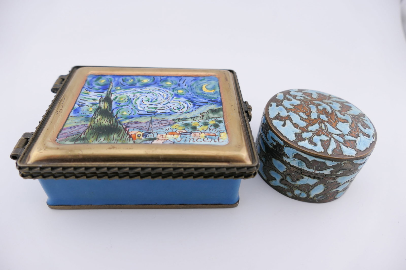 Two Cloisonne Trinket Boxes: Two cloisonne trinket boxes including a Kelvin Chen featuring an enameled lid motif of Van Gogh's Stary Night, alongside a vintage round box. Very good condition with minor color loss. Size: Larger