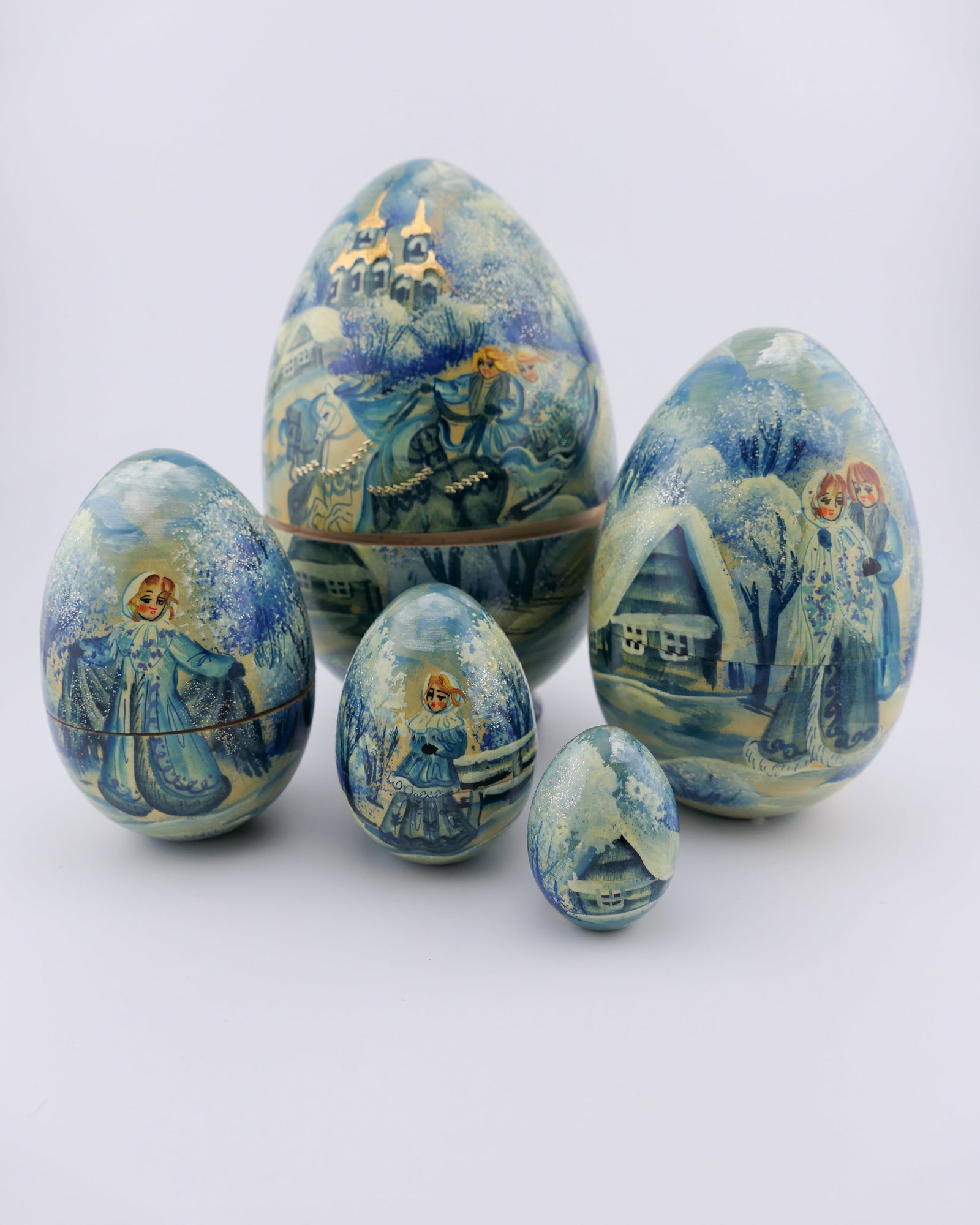 Hand painted Russian Matryoshka Egg: Hand painted Russian nesting egg in five layers, all featuring a matching winter troika scene with snowy trees, a house in the background, and a couple riding in a horsedrawn sleigh, all accented