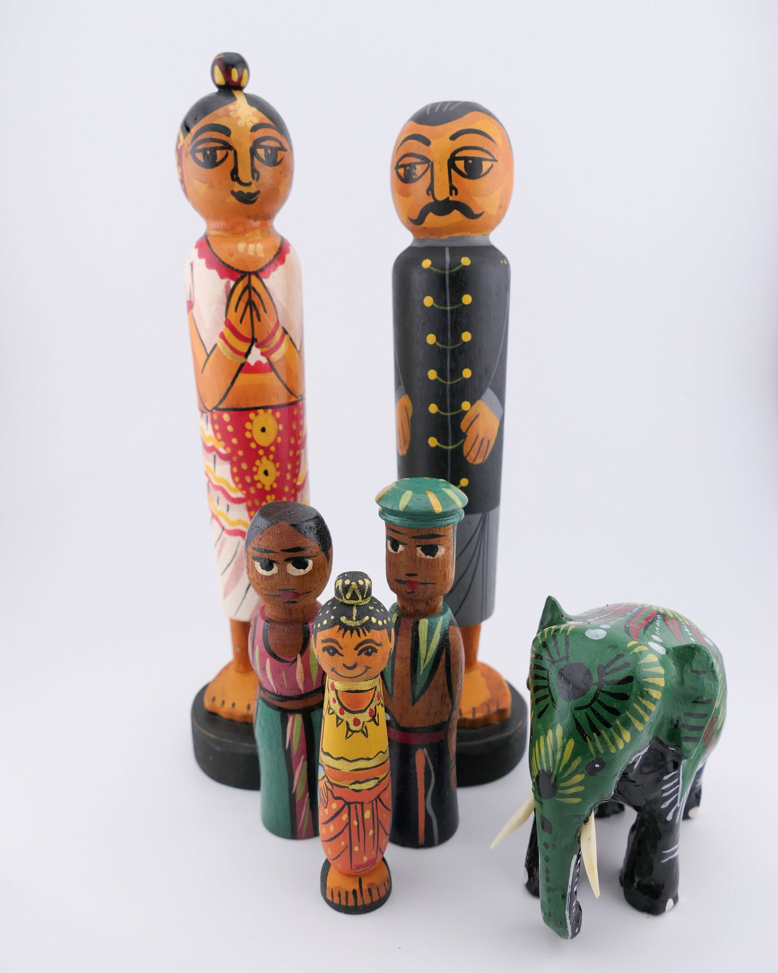 Five Hand Carved Folk Figurines: Five hand carved wooden folk figurines depicting people, and one elephant, all in hand painted detail. Two are marked Sri Lanka. Very good condition, with one elephant tusk needing regluing. Size: