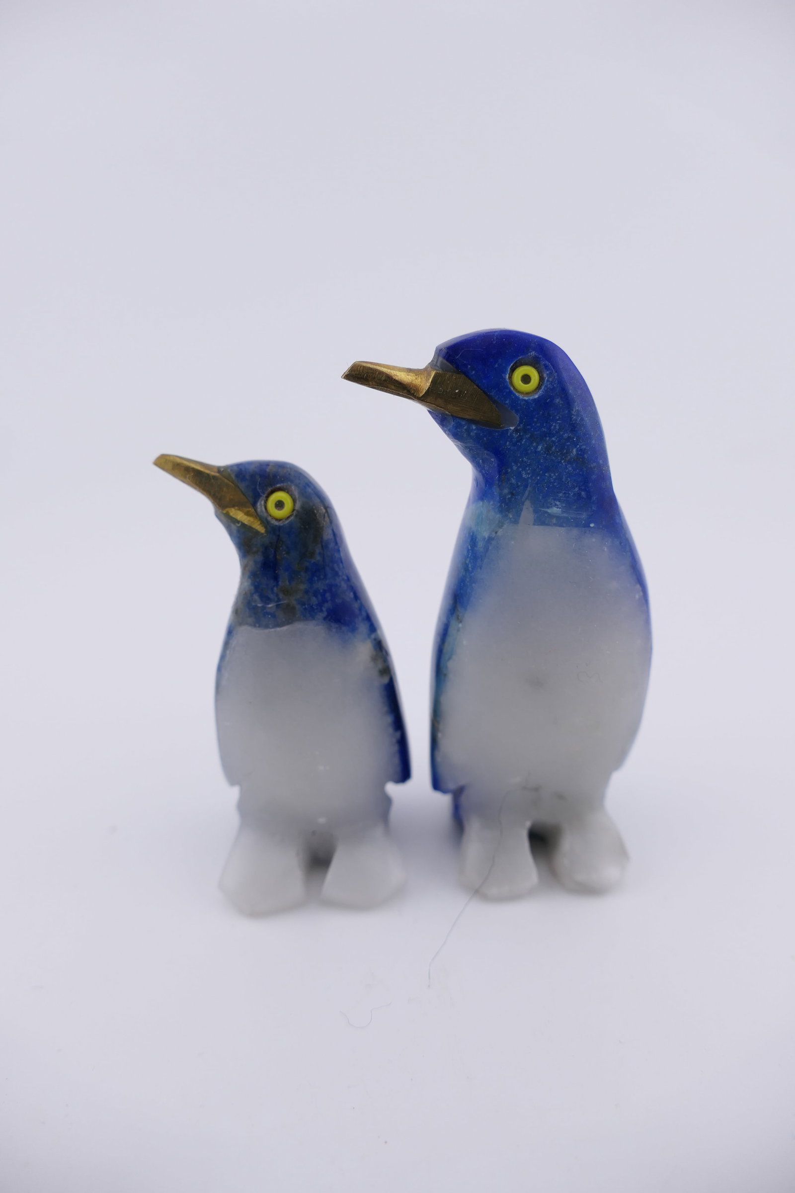 Two Lapis Lazuli Penguin Figurines: Two hand carved lapis lazuli penguin figurines featuring marble bellies and brass beaks. Size: 2.25"h Location: Living Room