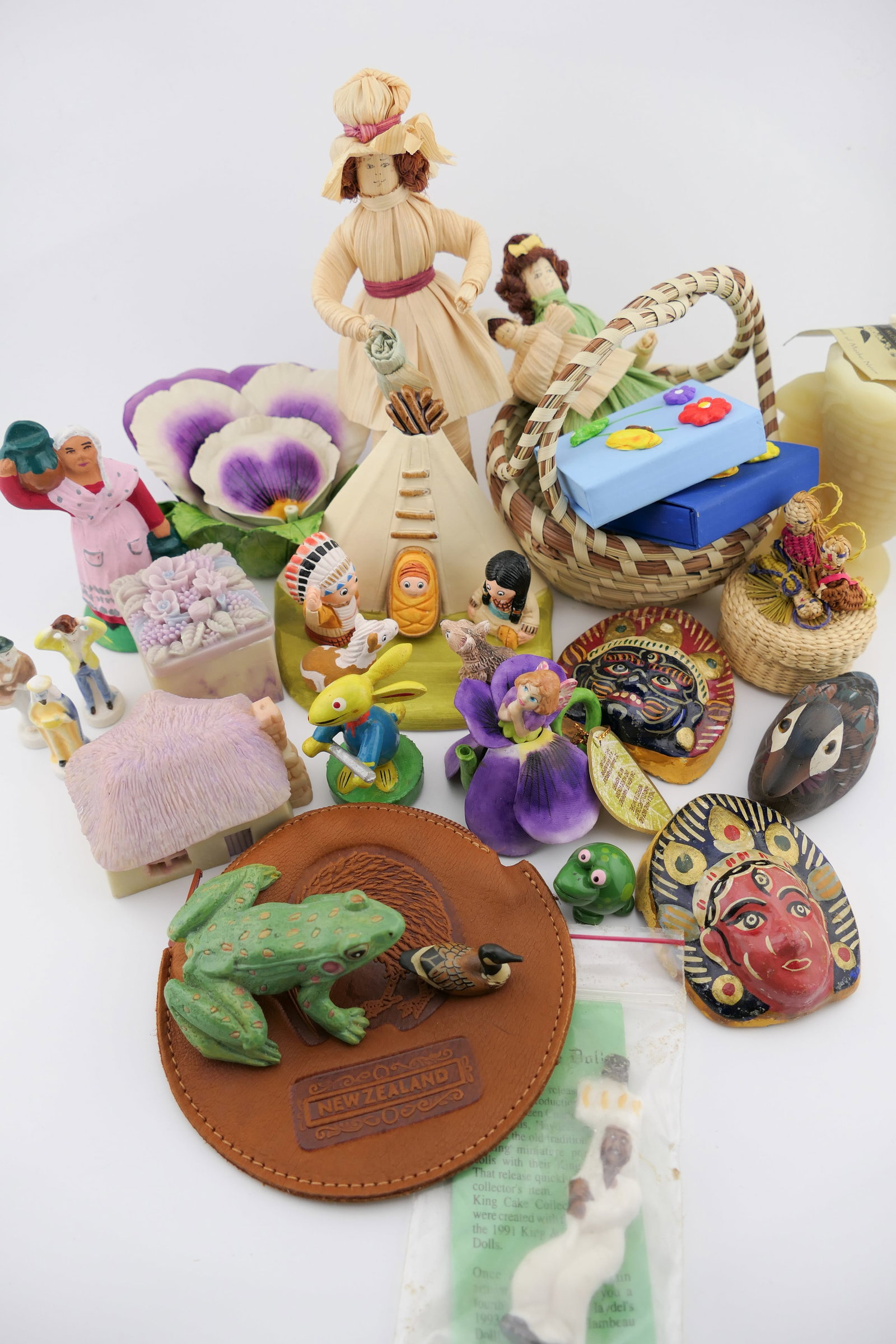 Collection of International Souvenirs: Collection of international travel souvenirs including a Khen ceramic fairy tea, and a pansy teapot marked Thailand, a hand carved wooden folk art rabbit in Erzgebirge style playing a flute, two corn