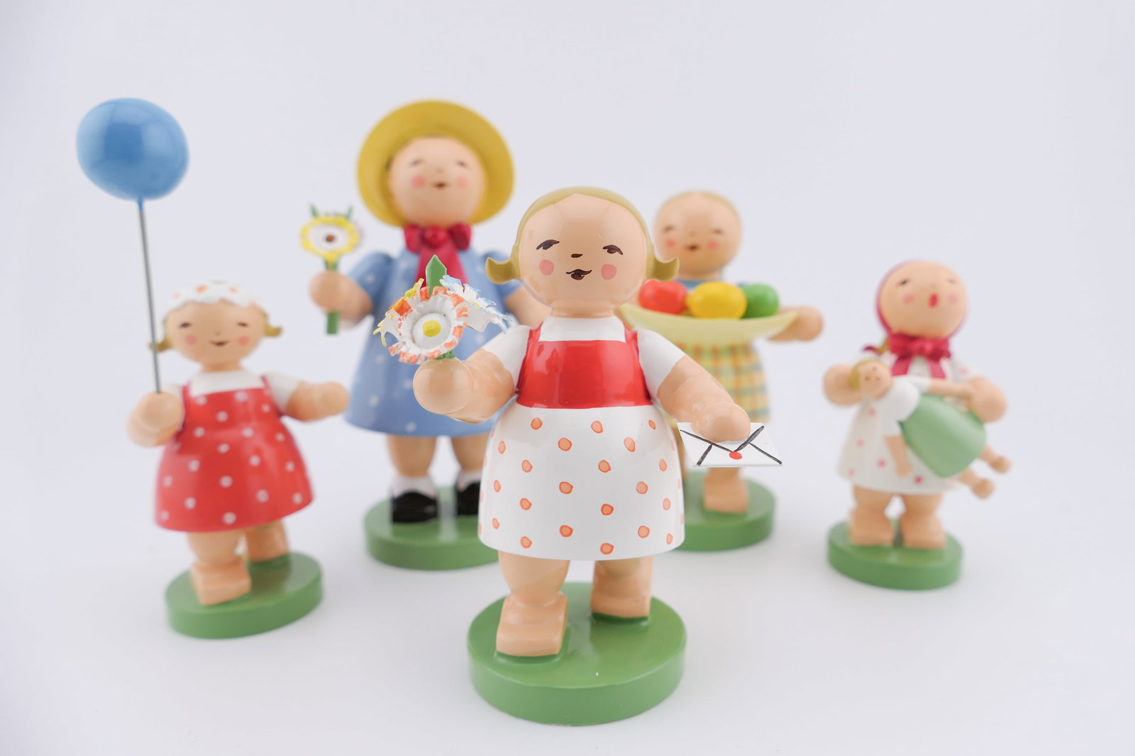 Five German Wooden Figurines: Five German-made wooden figurines by Wendt & Kuhn in spring themes, one holding painted eggs, flowers, a baby doll, and more. All are marked via stickers on the bottoms. Includes four original boxes.