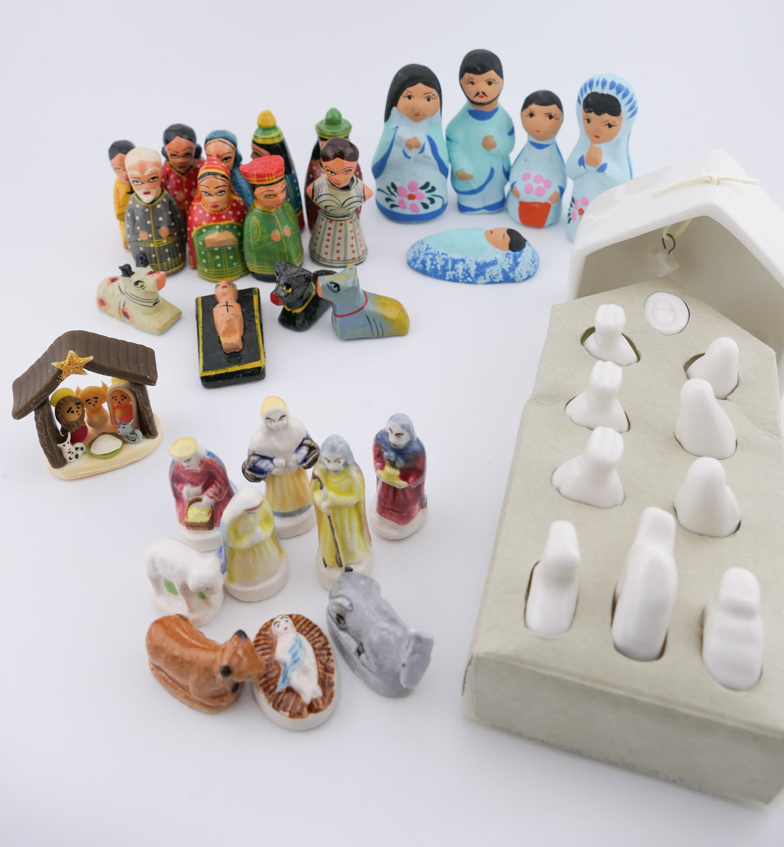 Three Miniature Nativity Scenes: Three miniature nativity scenes in international styles including a white glazed ceramic set marked East of India Porcelain, a Mexican-made blue hand painted clay nativity set, and a hand painted Indi