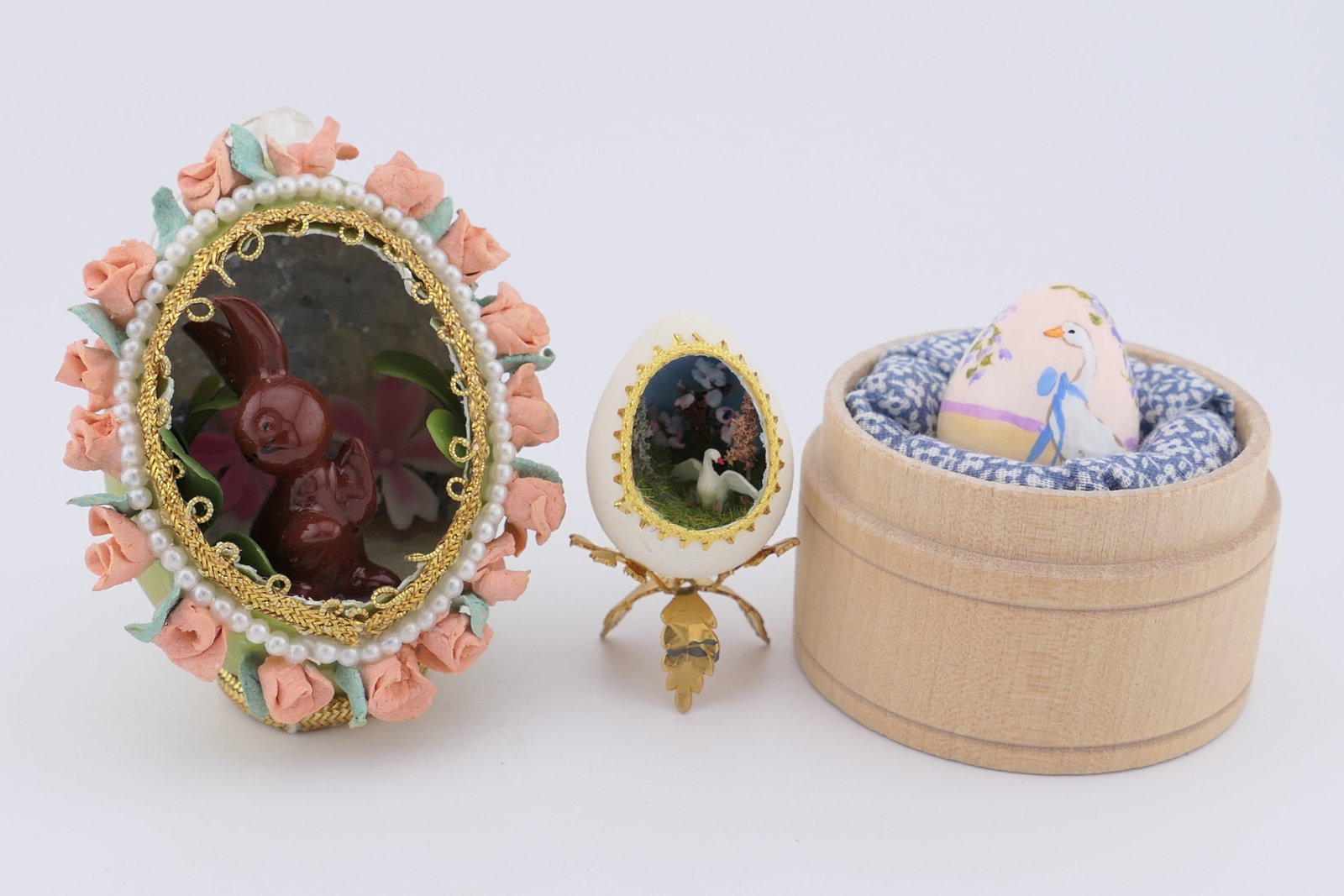 Three Hand-Crafted Egg Artworks: Three hand-crafted egg art pieces including one painted quail egg signed Edith, and one carved quail egg set with a miniature diorama containing a swan and landscape scene, alongside a carved chicken