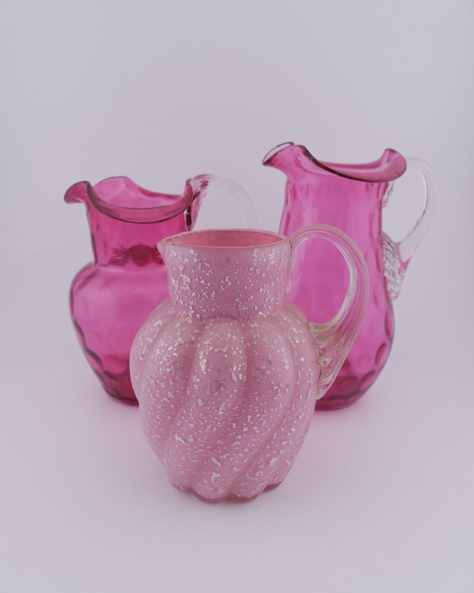 Three Pink Blown Glass Pitchers: Three pink blown glass pitchers including circa 1930-1950 pink satin with silver mica flecks and (2) coin spot pitchers. Excellent condition Size: Tallest 5.5"h Location: Living Room