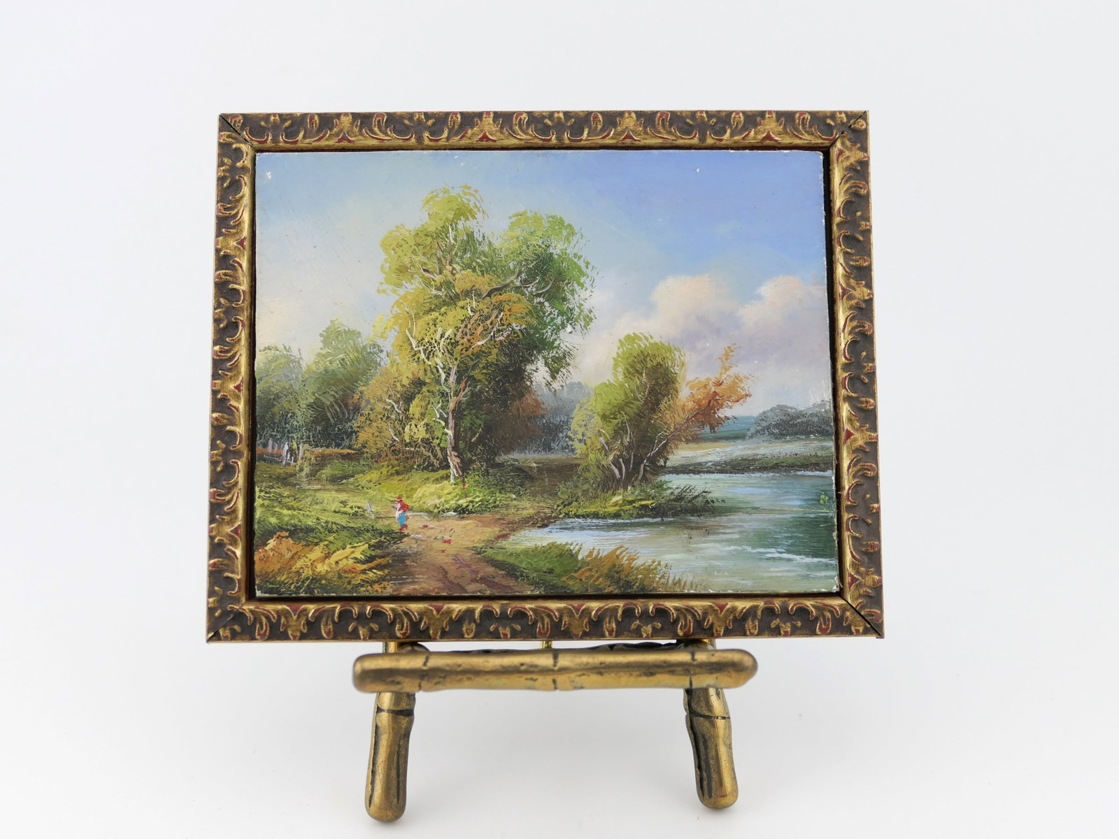 Miniature Oil on Board Landscape: Miniature oil on board pastoral landscape in gilt frame with brass easel. Very slight paint loss. Size: Exposed area of art 3.5"w x 2.75"h, frame 4.25"w x 3.25"h Location: Living Room