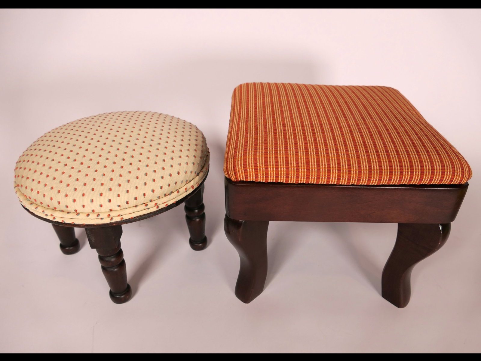Two Upholstered Foot Stools: Two small upholstered footstools including a striped orange fabric over a square frame with cabriole legs, alongside a circular stool with spotted fabric and turned legs. Very good condition. Size:
