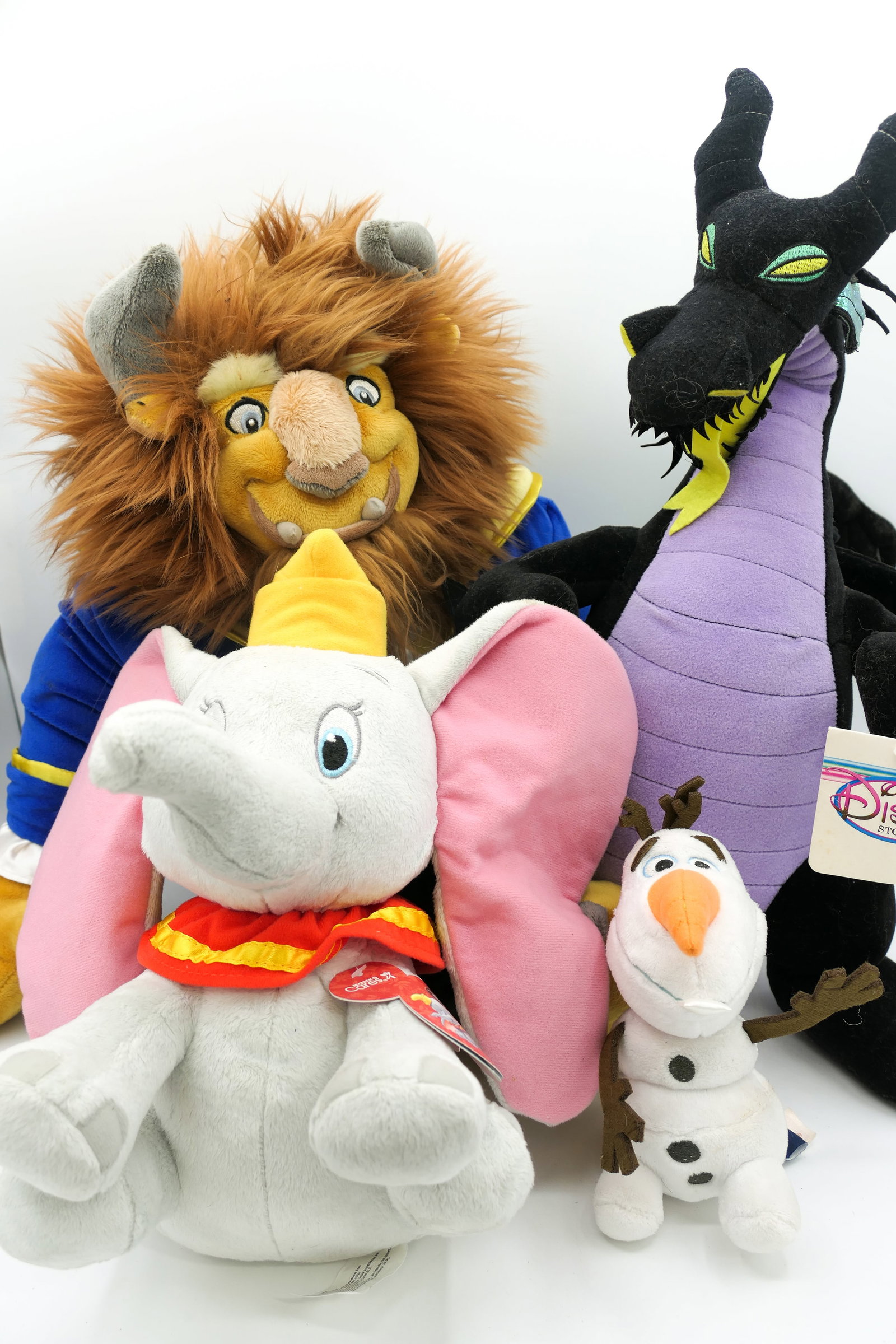 Four Disney Plush Toys: Four Disney plush toys including Maleficent Dragon, Olaf, Dumbo, and Disney Store Beast plush. Size: Largest 17"h