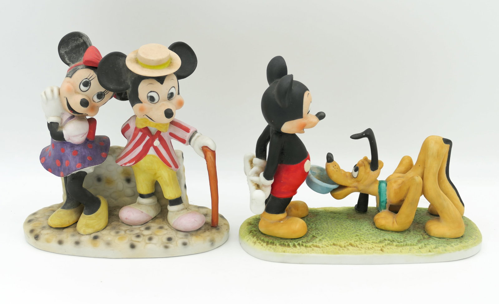 Mickey Mouse Ceramic Figurines: Two ceramic Disney figurines including Walt Disney Productions Mickey Mouse with Pluto and Mickey and Minnie dancing. Dancing figures show some finish loss. Size: Largest 6"w x 3"d x 6"h