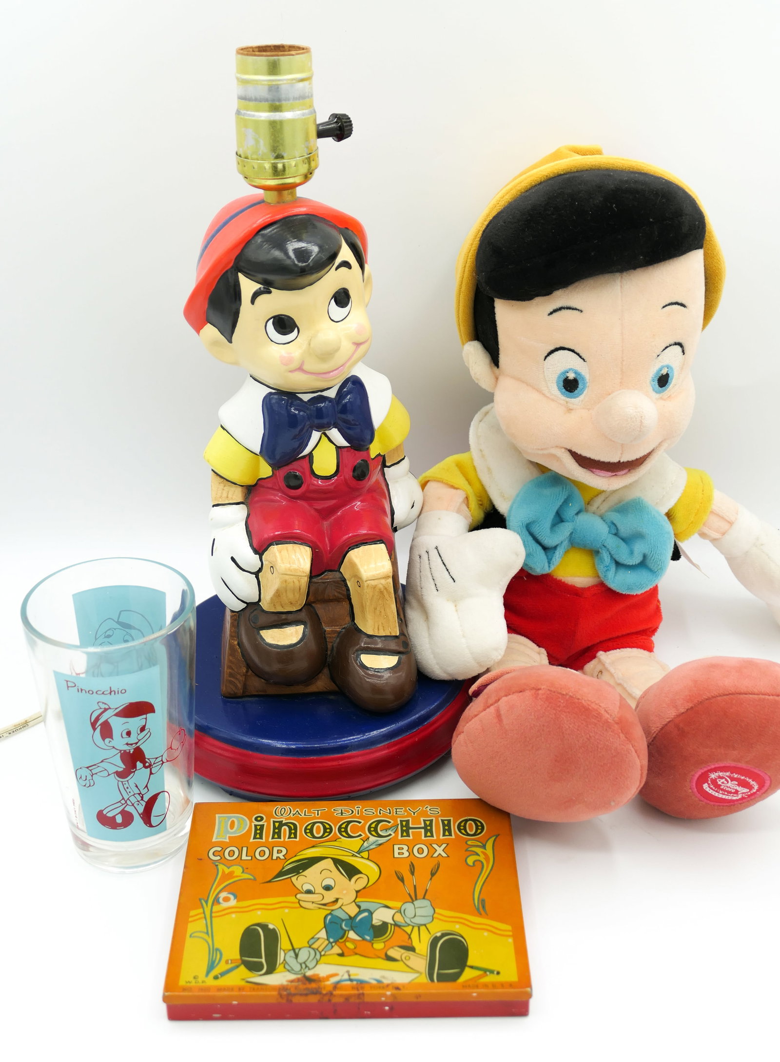 Pinocchio Collectibles: Pinocchio collectible items which includes a vintage Transogram Pinocchio Color Box, Walt Disney World Pinocchio figurine converted into lamp, Disney Store exclusive plush and a 5" drinking glass feat