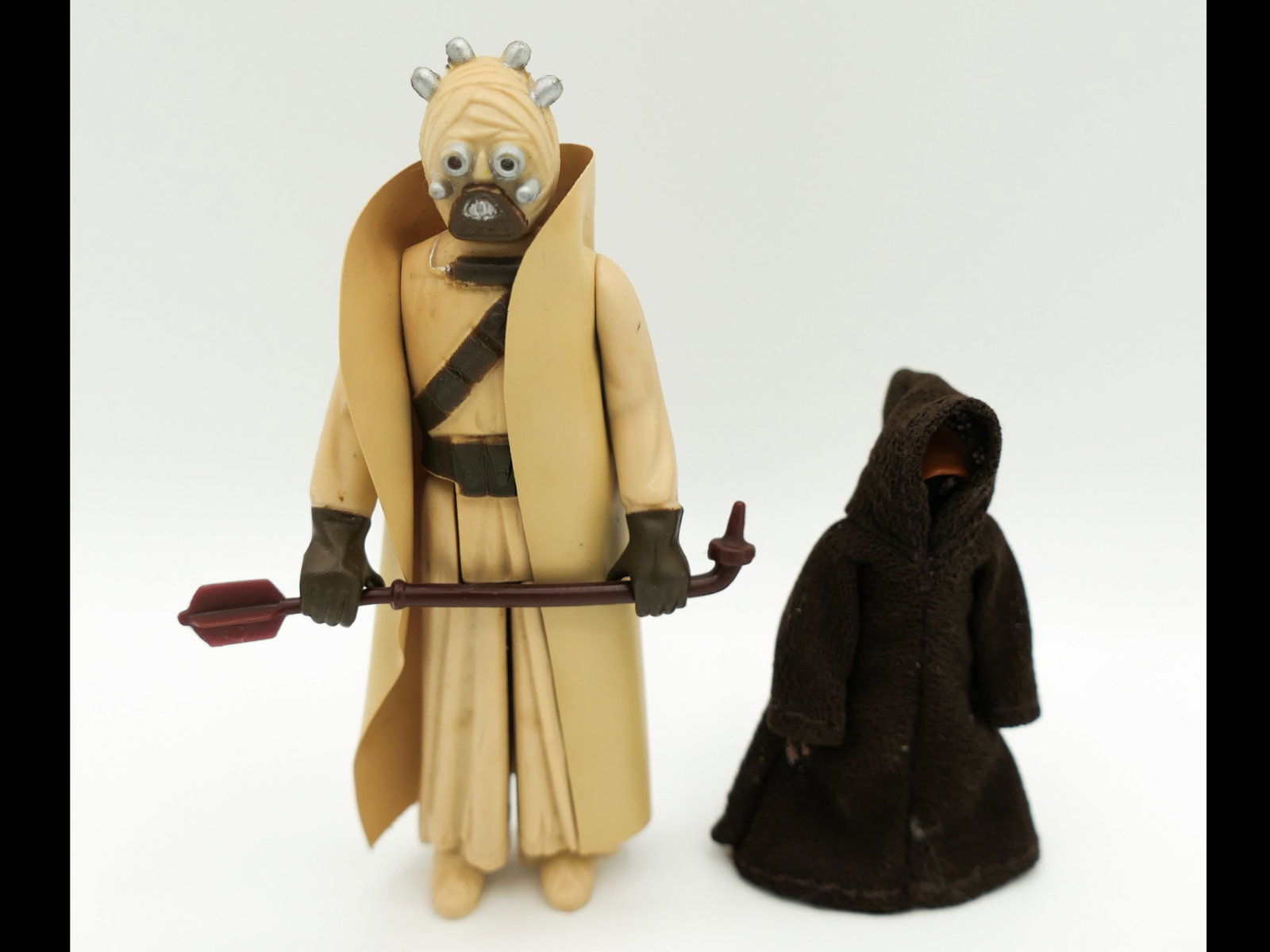 1977 Star Wars Action Figures: Two 1977 Kenner Star Wars action figures including a 4 inch Tusken Raider with weapon and a 2 inch Jawa in cloak. Size: 4"h