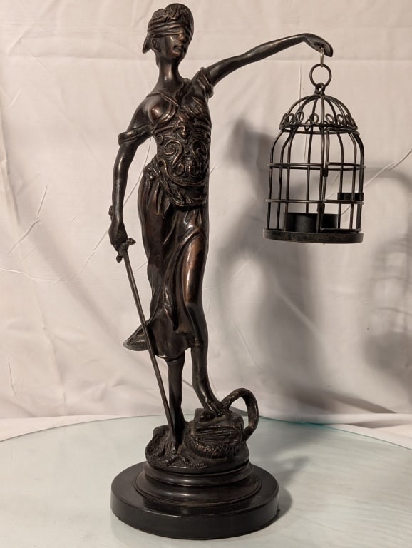 Lady Justice Statue - Bronze Modified: Lady Justice Statue - Bronze. Depicts figure with serpent at foot. Sword in hand. Scales have been replaced with a birdcage tealight holder. No markings, black base shows minor wear. Meas. 15"h x 7 1/