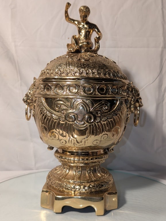 Covered Urn w/ Lid - Cast Brass Maitland Smith: Large Covered Urn w/ Lid - Cast Brass by Maitland Smith. Mid 20th century. Cherub finial at top of lid. Lion head rings on either side. Exquisitely detailed. Mint condition. On square base. Meas. 17"h