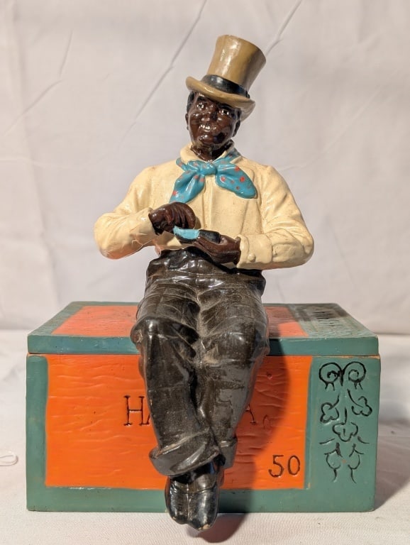Black Americana Cigar Box, Man in Top Hat on Box: Black Americana Cigar Box, Man in Top Hat and Scarf, Smoking a Cigar, Holiding an Ashtray while sitting on Box. Painted cast iron. Colorado Habana 50. Etched scroll design on box. Shows