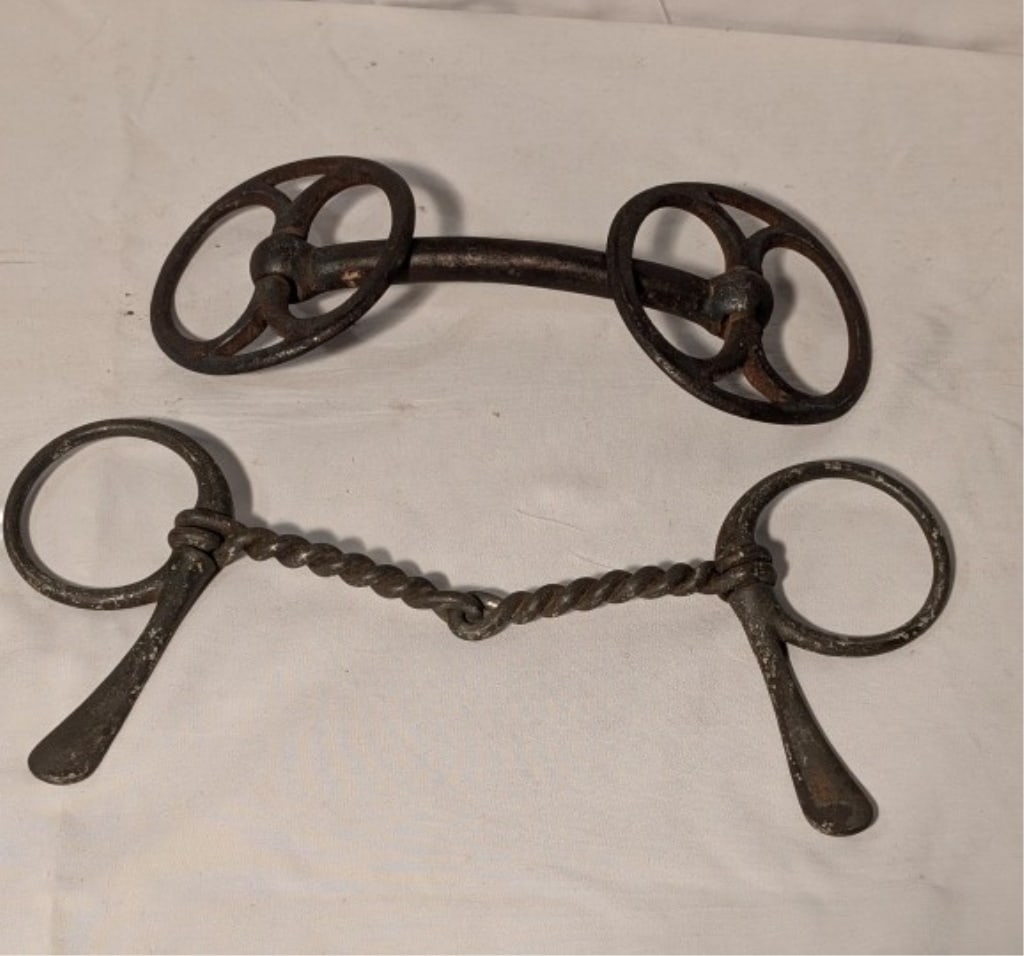 Antique Working Draft Horse Bits (Pair)-Cast Iron: Antique Working Draft Horse Bits (Pair) - Cast Iron. One has a rope like design connection w/ round loop bits. Meas. 4 1/4"h x 10 1/2"w. The other has solid metal center bar w/ wheel bits. 