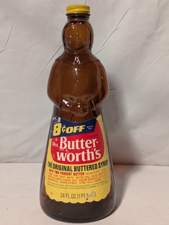 1975 Mrs Butterworth Amber Syrup Bottle Screw Top: 1975 Mrs Butterworth Amber Glass Syrup Bottle, Metal Screw Top and label w/ 8cents off Coupon. 24oz. Some loss on label and on cap. Cost $1.29 stamped on cap. Lever Brothers Company NY. Meas