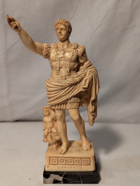 Cesar Augustus Roman Alabaster Statue: Cesar Augustus Roman Alabaster Statue. P.A.T. marked on top corner of black marble base. Cherub by Leg. Greek keys around the perimeter of the base. Meas. 9 1/2" x 3"sq at base.