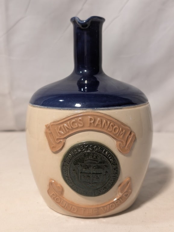 Blue Earthenware Jug "King's Ransom": Blue Earthenware Jug w/ Stopper,"King's Ransom Round The World". Base of jug is natural color, top is blue enamel. Raised relief ribbon contains title. Center black emblem. Made in England. Also has r