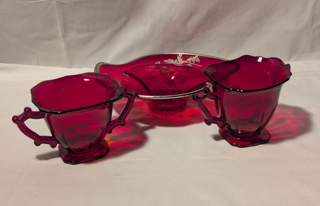 '60s Ruby Red Glass Sugar Bowl Creamer, Candy Dish: 1960s Ruby Red Glass Sugar Bowl & Creamer are a matching set with ribbed design, slight ruffle on rim and short pedestal base on each. Meas 3"h x 6"w x 4"d. Candy Dish has silver rim, with silver