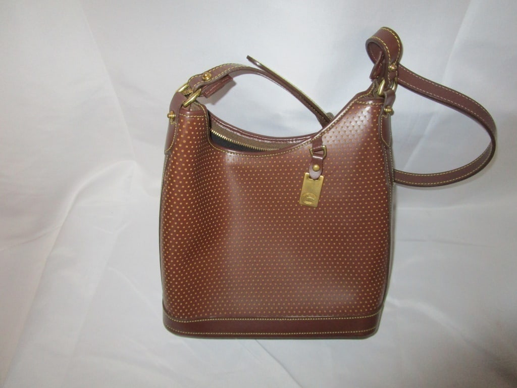 Vtg Dooney & Bourke Brown Cabrio Hobo Bag: Vtg Dooney & Bourke Brown Cabrio Hobo Bag. Brown with polka-dot reticulated design. Brass accents, brass and leather logo key fob on front. Brass feet, Zippered top close. Inside side zippered pouch. 
