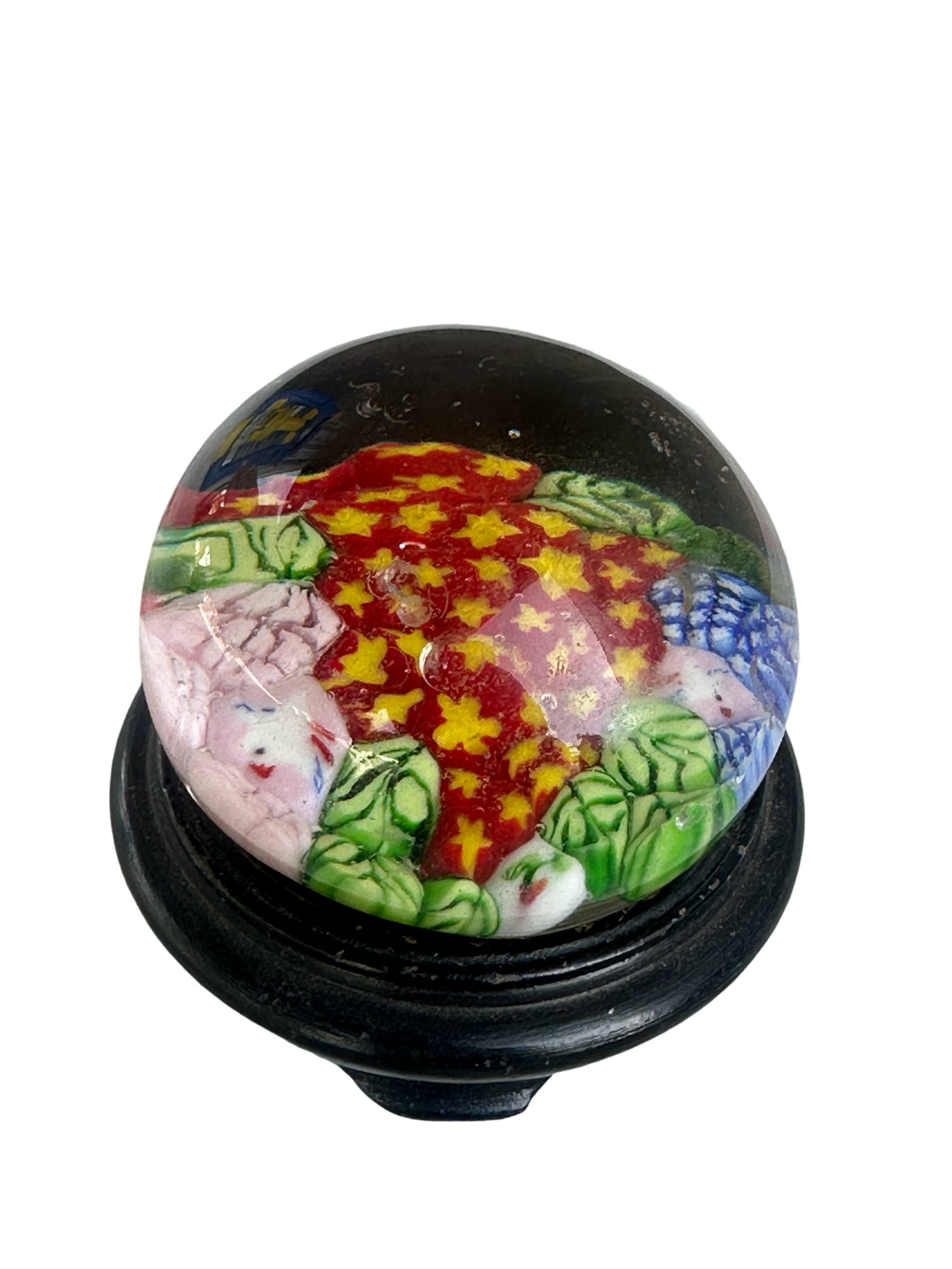 MURANO Millefiori Art Glass Paperweight: MURANO millefiori art glass paperweight with floral inclusions in hues of red, pink, blue, yellow, and green encased in transparent glass.Measures approx. 2.25x7.5 inches around. surface wear consiste
