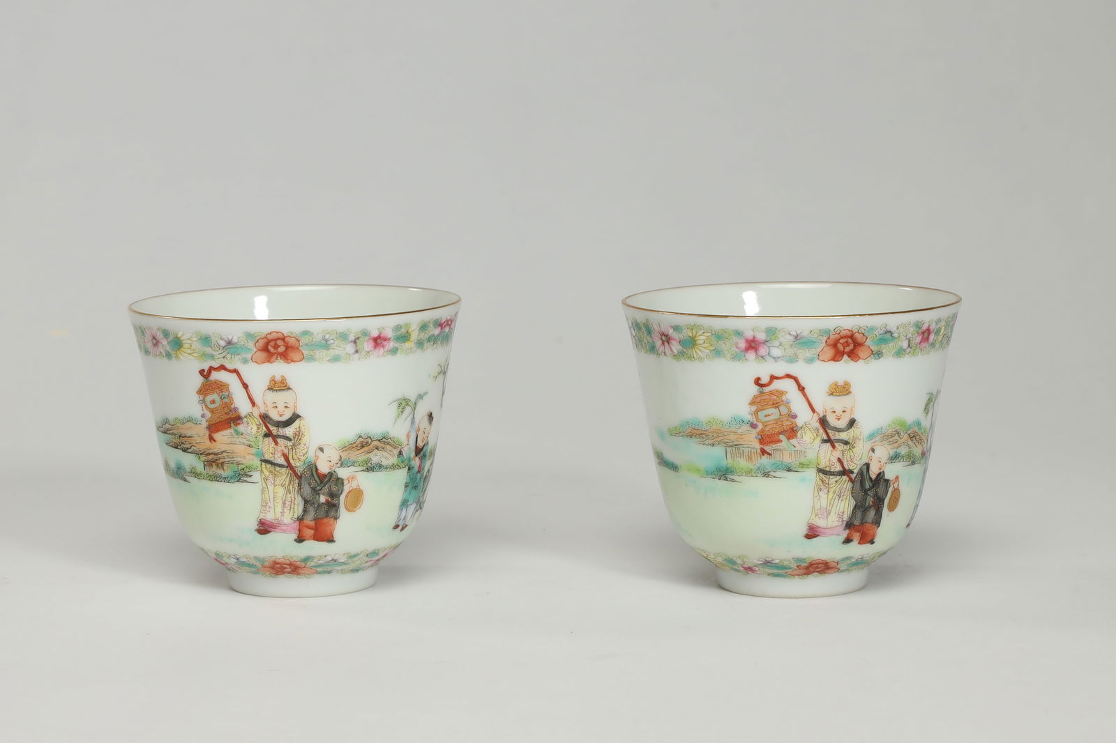 A PAIR OF PASTEL CUPS WITH BABY PLAYING: H6.4cm W5.3cm