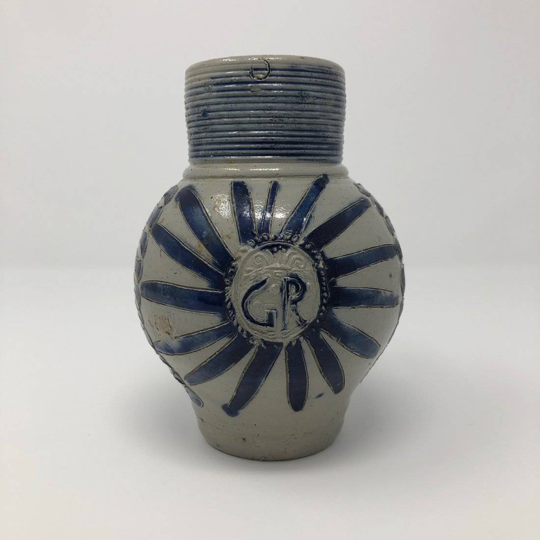 GR Rhenish Stoneware Mug, King George II: A gray salt glazed mug with cobalt blue star burst ray designs coming out of an impressed medallion marked GR, for Georgius Rex, or King George. The top neck has blue rings, vs. more common purple rin