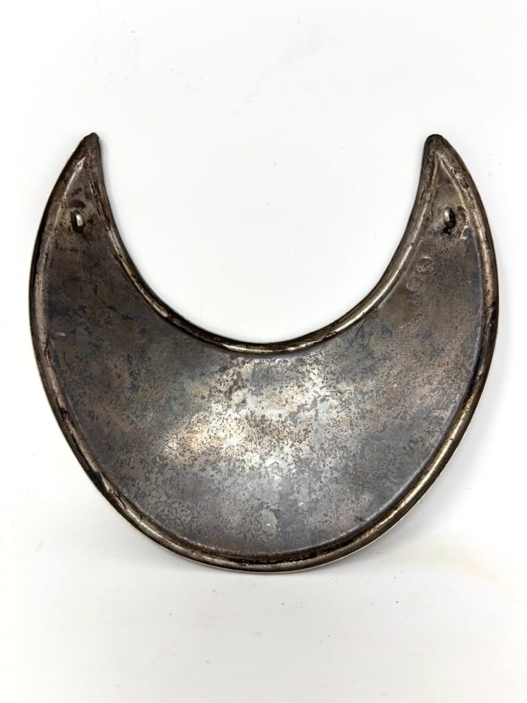 Early Trade Silver Gorget Stamped XX: Offering an early Trade Silver Gorget stamped “XX” with a Lion cartouche in the top left side. It measures 4 3/4” high x 5 1/4” wide. The front center is engraved with a peddled fl