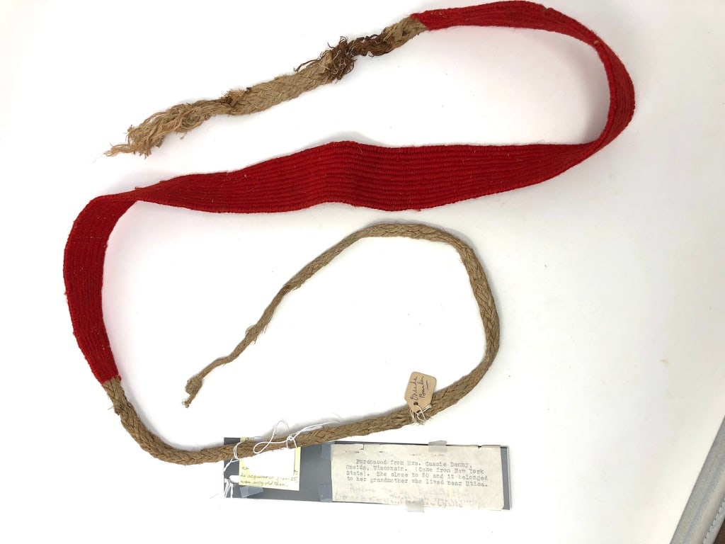 Indian Burden Strap: An Indian Burden strap with red dyed weaving and fiber weaving straps. 2” wide x 28” long without ties; ties 27” & 10” long (torn off long ago.) Part of one strap is broken