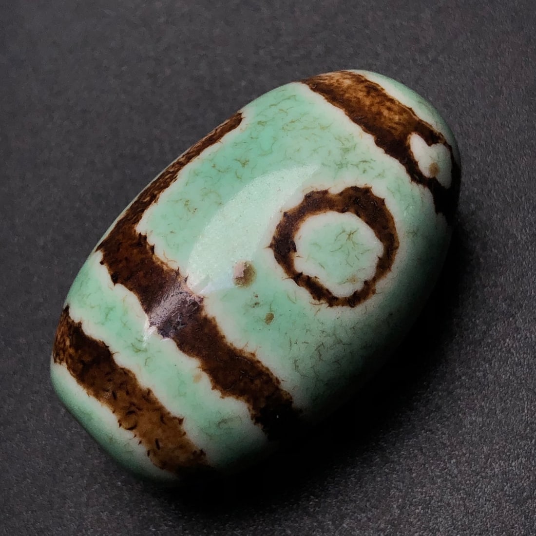 Two-eyed Tibetan bead: Two-eyed Dzi bead. Dimensions: 39x24x21 mm. Weight: 29.1 grams. The totem is clear and smooth, with visible horseshoe patterns and a rich patina. The design symbolizes a jade tree with intertwined bra