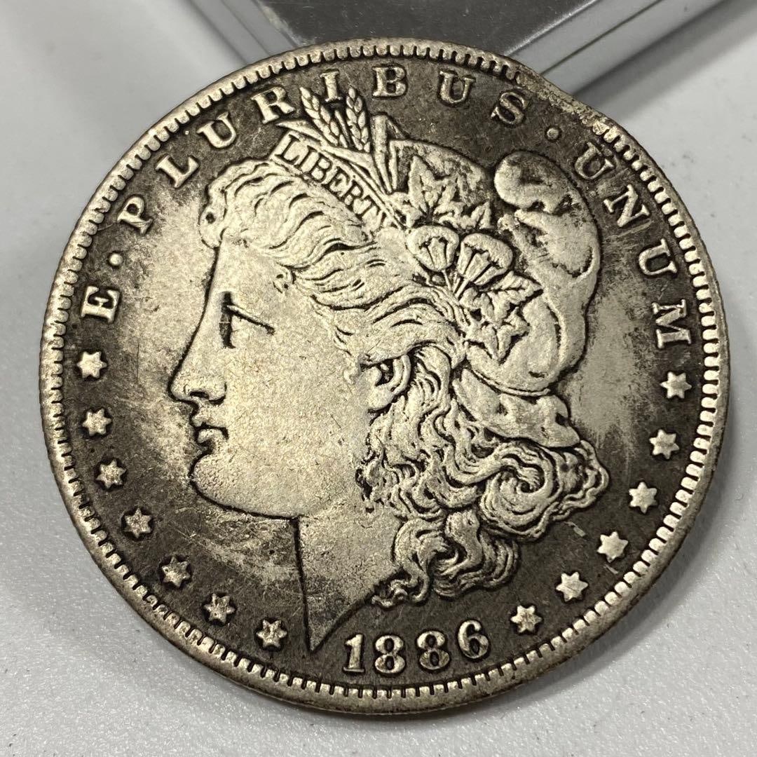 1886 Morgan Silver Dollar, $1, American cultural coin.: This is an ancient coin, with a side profile of the Statue of Liberty engraved on it, along with the words "EPLURIBUS UNUM" (United States motto) and "LIBERTY".