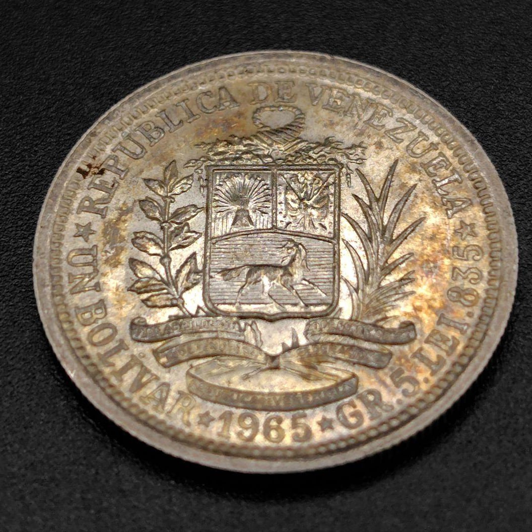 Venezuela 1 Bolivar silver coin: This is a Venezuelan 1 Bolivar (UN BOLIVAR) silver coin issued in 1965. Coin Details: Country: Republic of Venezuela (REPÚBLICA DE VENEZUELA) Denomination: 1 Bolivar (UN BOLIVAR) Material: Silver (pu