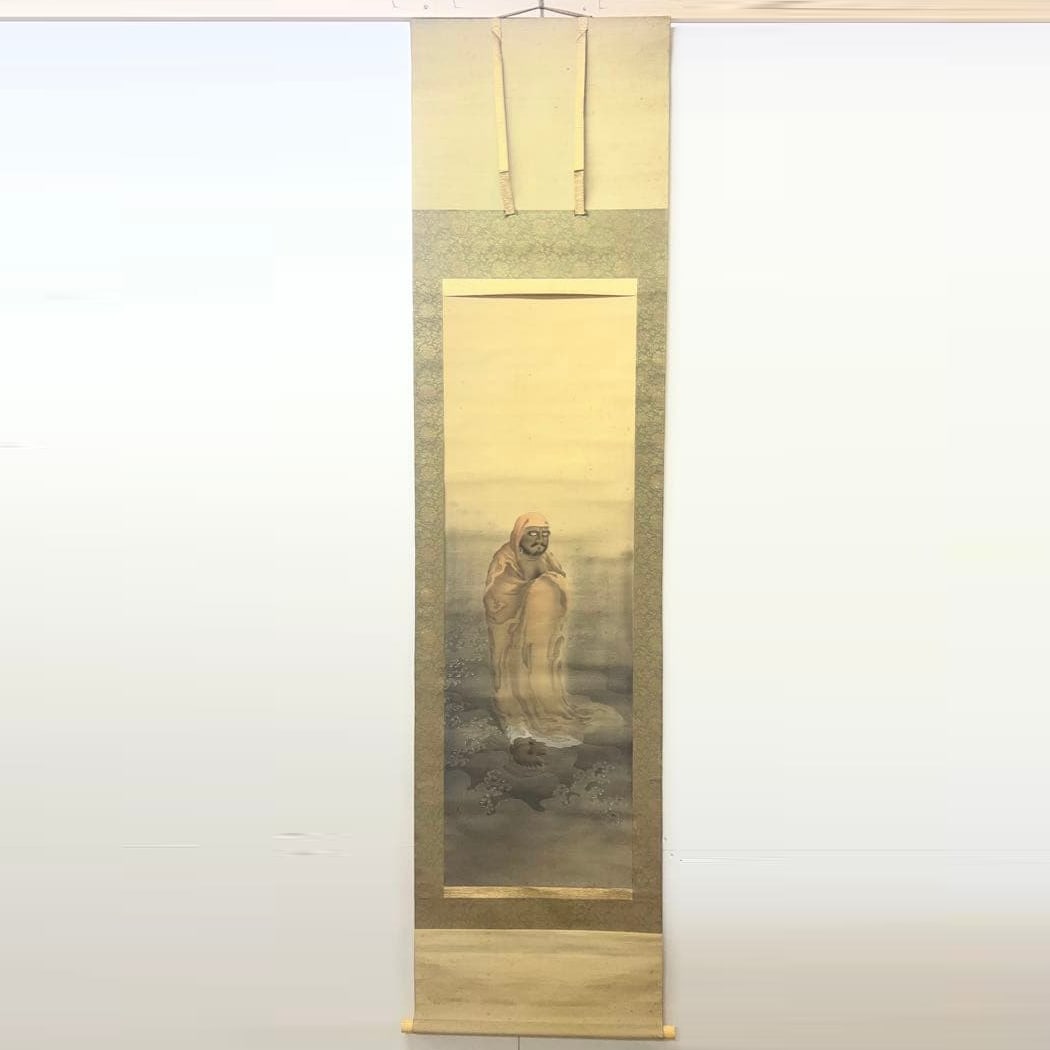 Japanese silk hand-painted portrait of Daruma.: A Japanese painting hanging scroll, featuring soft colors and depicting a figure. Technique: Japanese painting Subject: Human Color scheme: Light colors Mounting dimensions: approximately 214 x 53.5 c