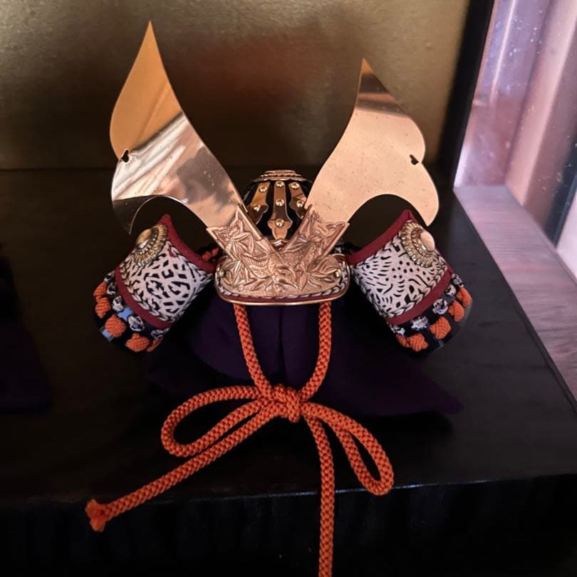 Miniature Helmet: This is a miniature model of a traditional Japanese helmet. It is meticulously crafted, with great attention to detail. As it is placed in a glass case, there are no visible stains, discoloration, scr
