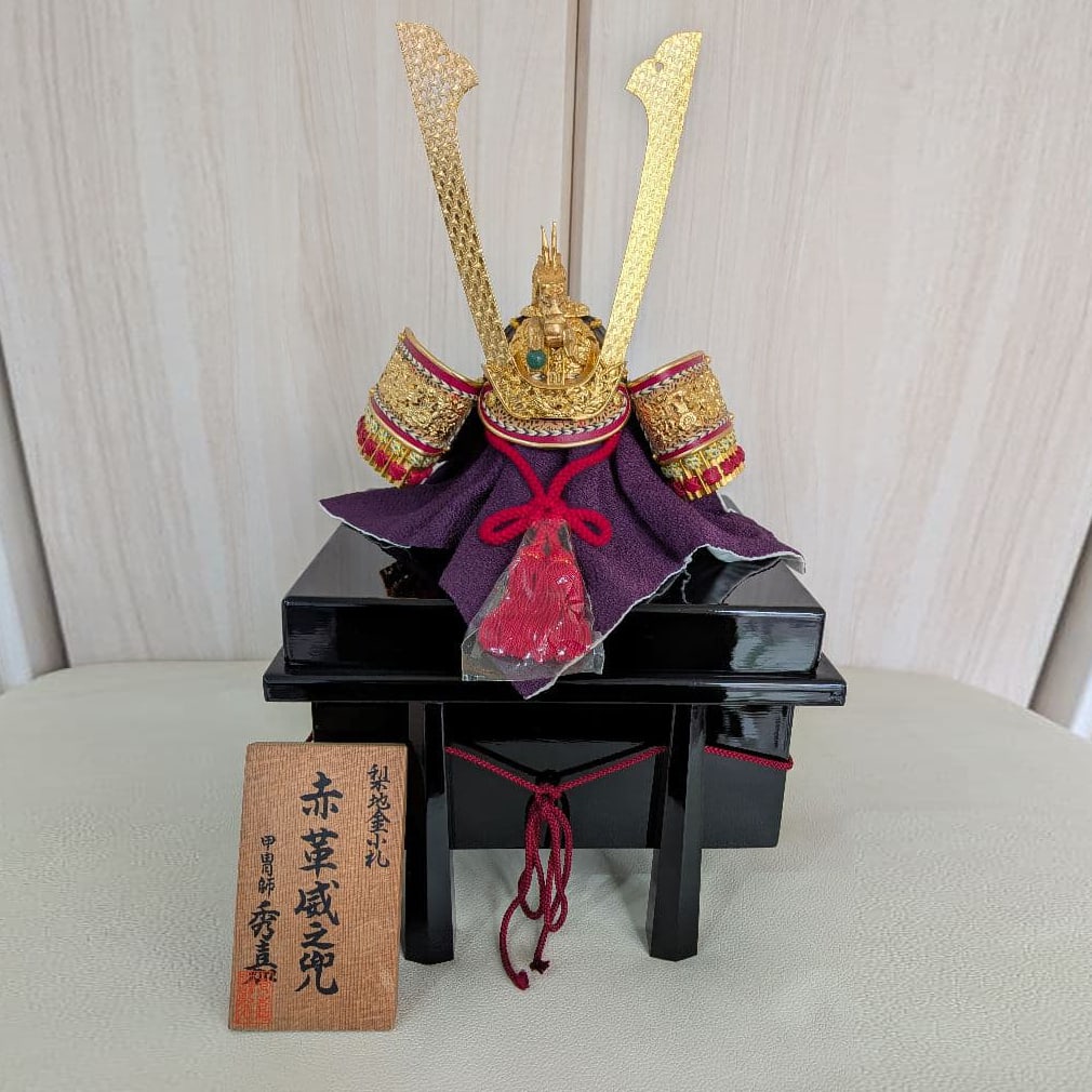 A red leather laced helmet (miniature helmet) by the armorer "Toyotomi Hideyoshi".: This is a handcrafted masterpiece, made with pure silk threads dyed in Kyoto, a bowl inlaid with stars, a genuine jade ball stand, and a wood-carved, gilded dragon head. Storage box dimensions: approx