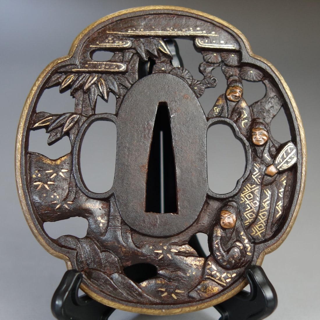 Masterpiece of Antiques: A Gilt Bronze Inlaid Sword Guard with Pine and Bamboo Pattern in Openwork: This sword guard features intricate openwork carving, depicting three nobles gathered under pine and bamboo, with an iron background. The faces of the scholars are inlaid with copper, the patterns on 