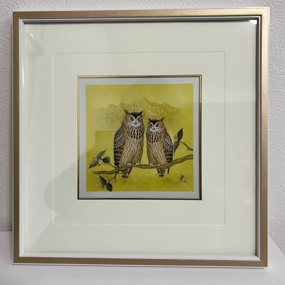 A painting of an owl set against a yellow background, mounted in a metal frame. (1 of 3)