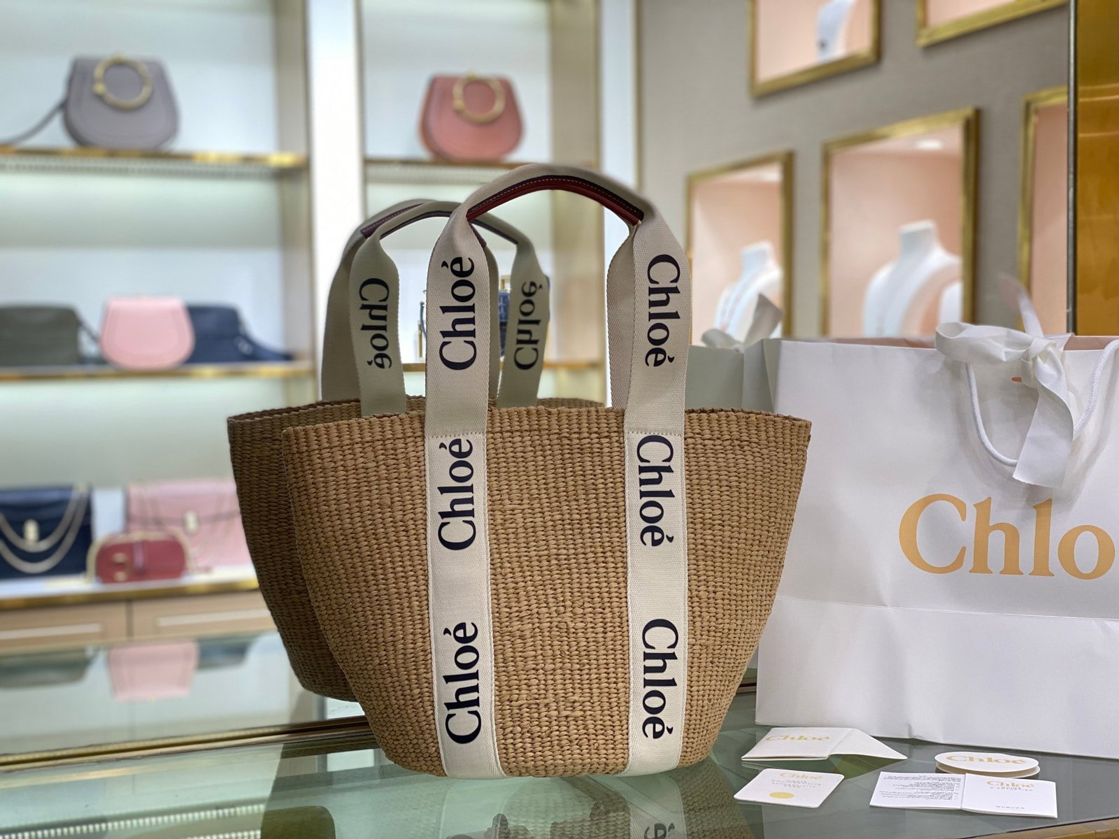 Chloe: The Large Woody Basket features a Woody ribbon and a classic basket design for a relaxed summer vibe. It can be carried by hand or over the shoulder. The bottom of the basket is protected by a Chloe e