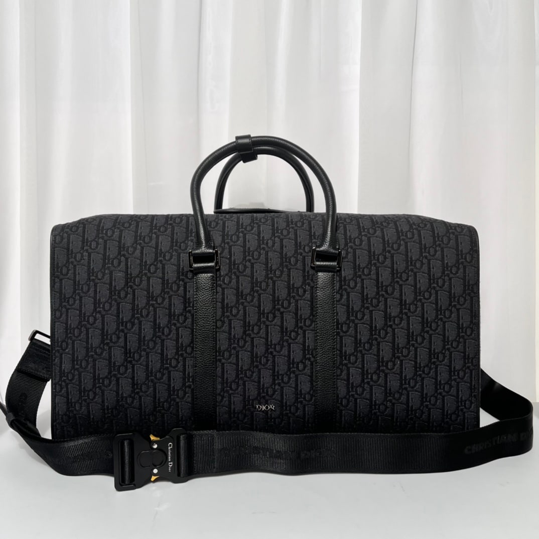 Christian Dior: The Dior Lingot 50 handbag is practical, elegant, and unique. Crafted from beige and black Oblique printed fabric, it features black grained calfskin details for added sophistication, and is adorned w
