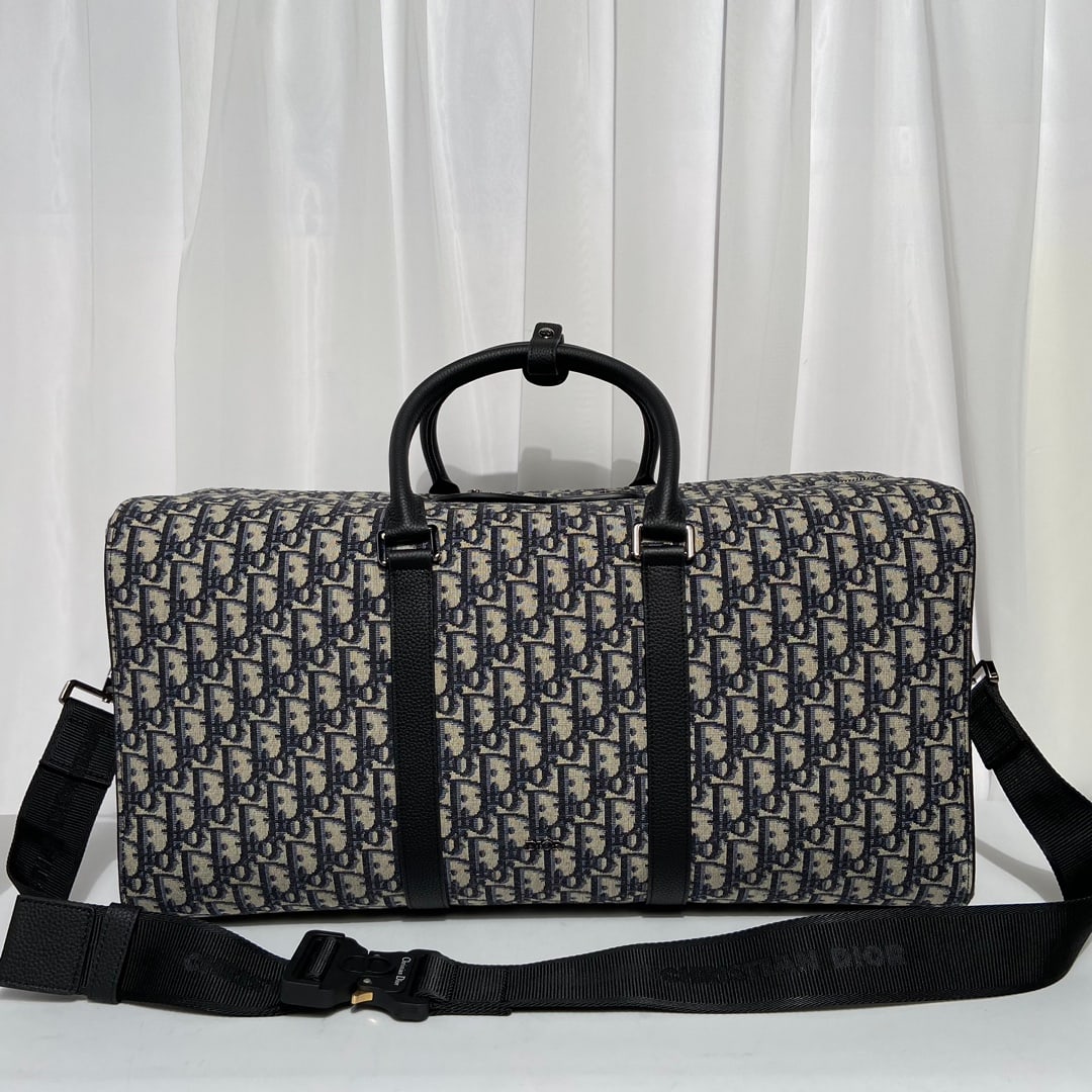 Christian Dior: The Dior Lingot 50 handbag is practical, elegant, and unique. Crafted from beige and black Oblique printed fabric, it features black grained calfskin details for added sophistication, and is adorned w
