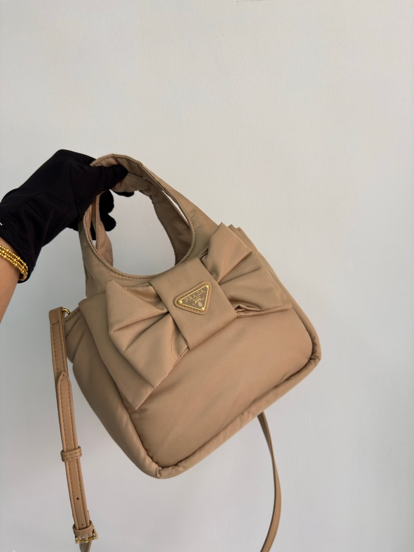 PRADA Re-Nylon handbag: This recycled nylon handbag, with its padded design, blends subtle contrasts with classic details, showcasing a romantic yet unconventional fashion spirit. The soft silhouette paired with a minimalist