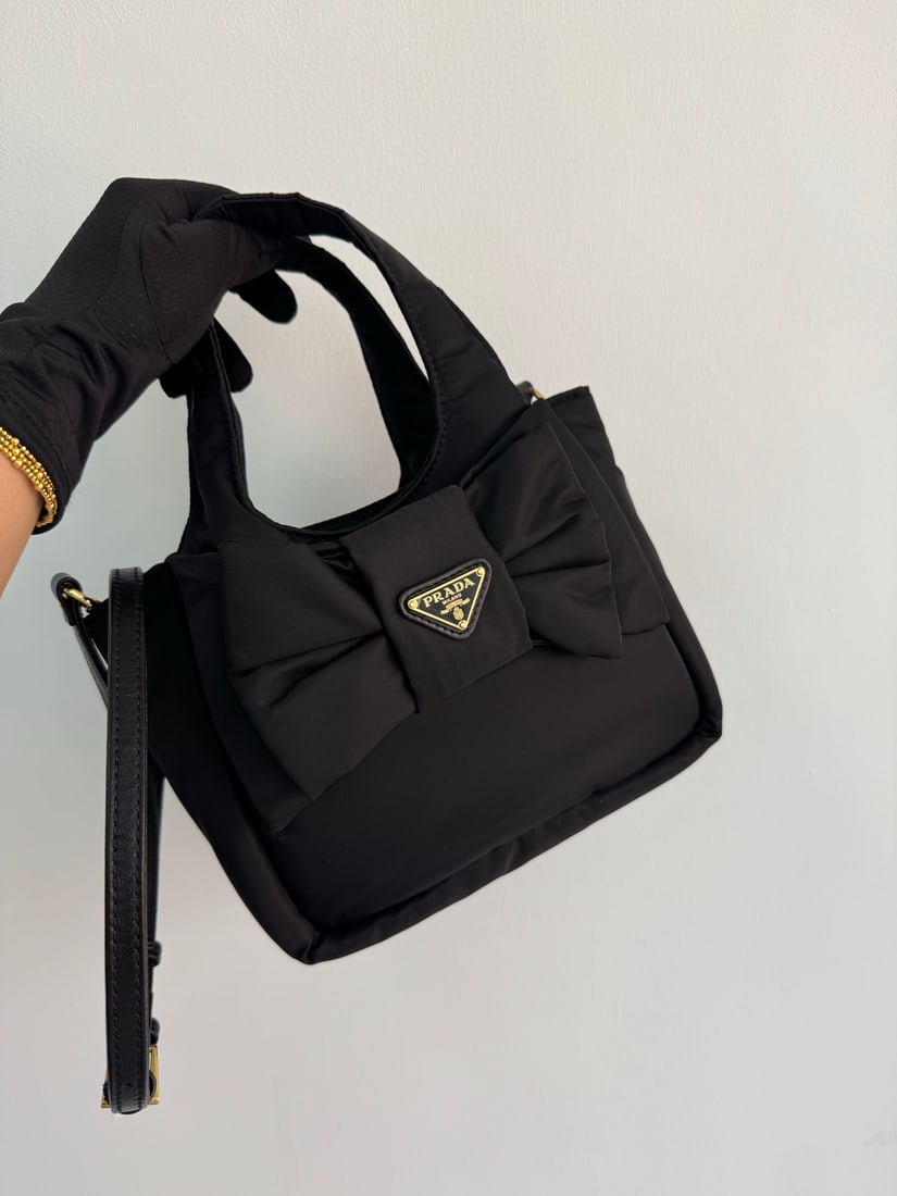 PRADA Re-Nylon handbag: This recycled nylon handbag, with its padded design, blends subtle contrasts with classic details, showcasing a romantic yet unconventional fashion spirit. The soft silhouette paired with a minimalist