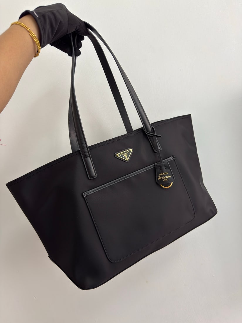 PRADA Re-Nylon handbag: The timeless tote bag is a reinterpretation of classic design, crafted from imported nylon fabric, showcasing a unique style with a refined yet practical silhouette. Its clean, elegant lines, spacious