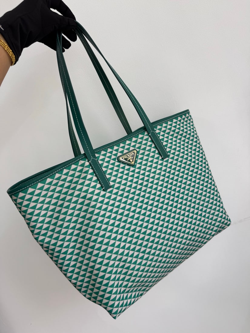 PRADA Tessuto Triangulum Tote Bag: The Tessuto Triangulum tote bag is made of imported printed nylon fabric and paired with cross-grain cowhide. The eye-catching triangular pattern and vibrant colors, combined with its large capacity, 