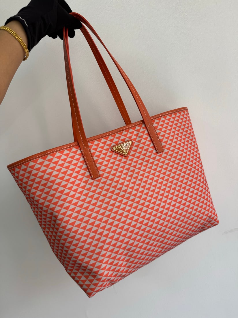 PRADA Tessuto Triangulum Tote Bag: The Tessuto Triangulum tote bag is made of imported printed nylon fabric and paired with cross-grain cowhide. The eye-catching triangular pattern and vibrant colors, combined with its large capacity, 